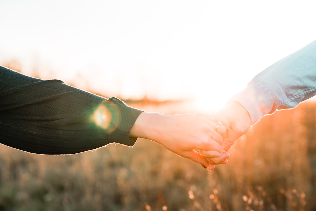Two hands clasped together in comfort and support